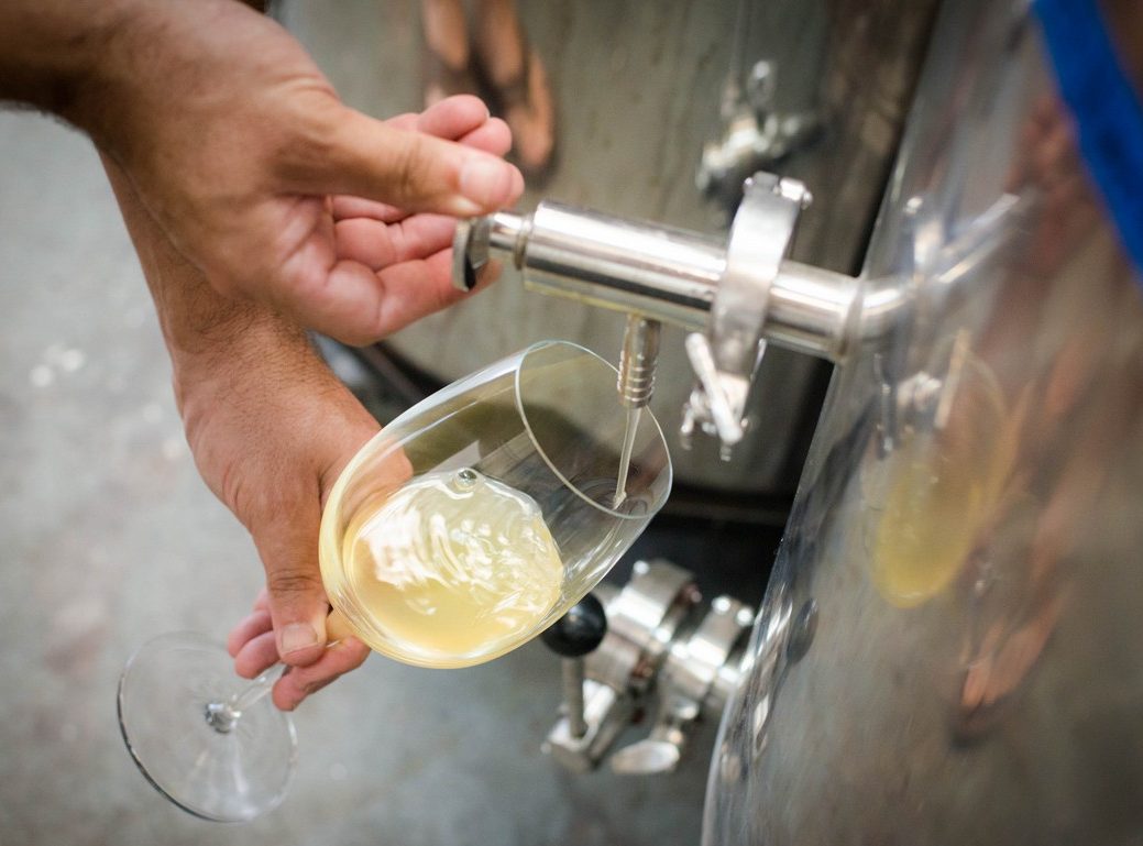 Wine being poured from tank tap into glass
