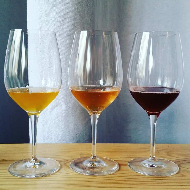 Three wine glasses with white, rose, and red wine